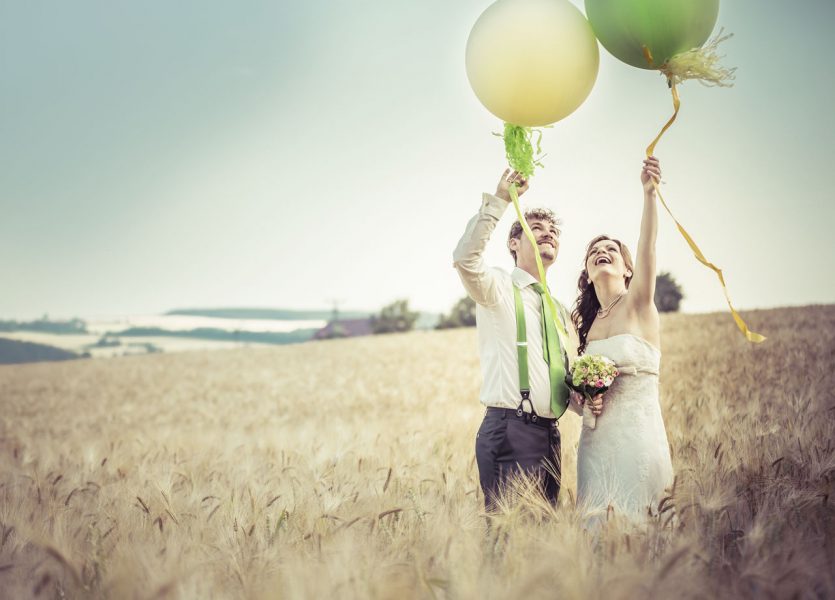 Brautpaar mit Luftballons im Kornfeld